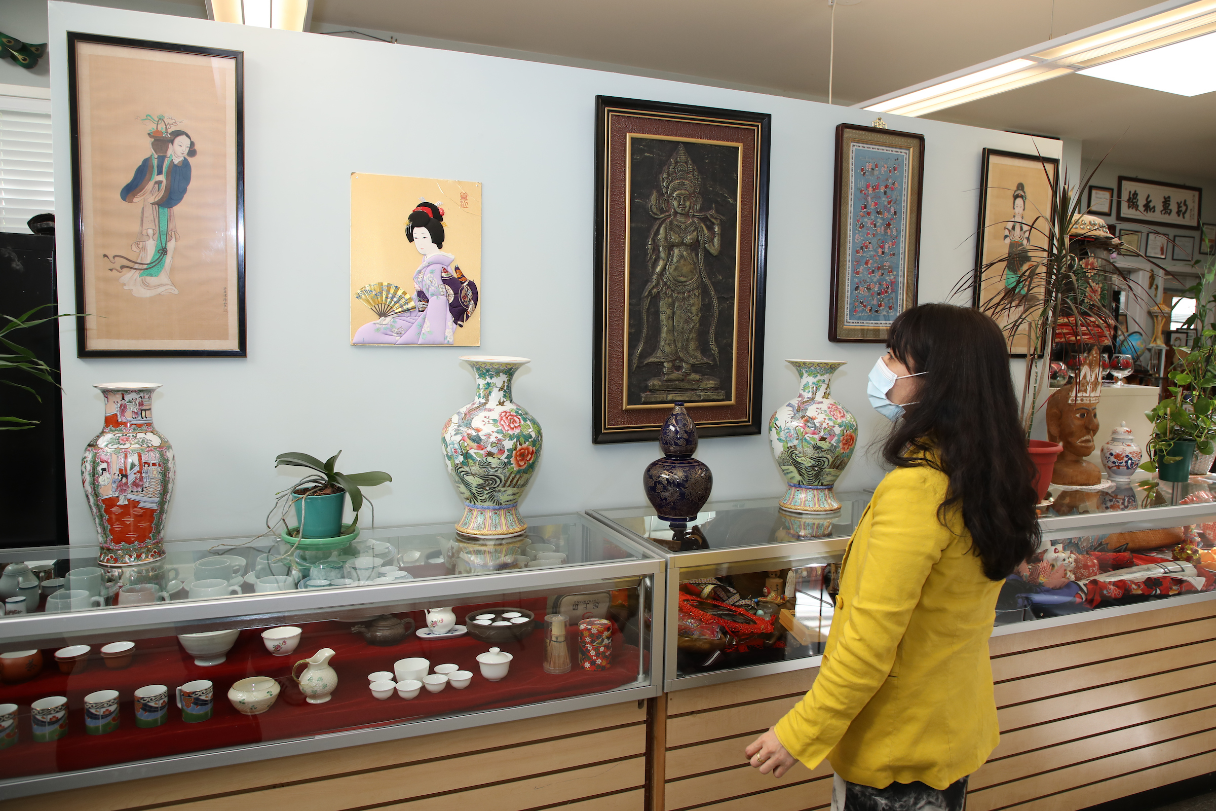 photo of a woman in a mask looking at art on a wall
